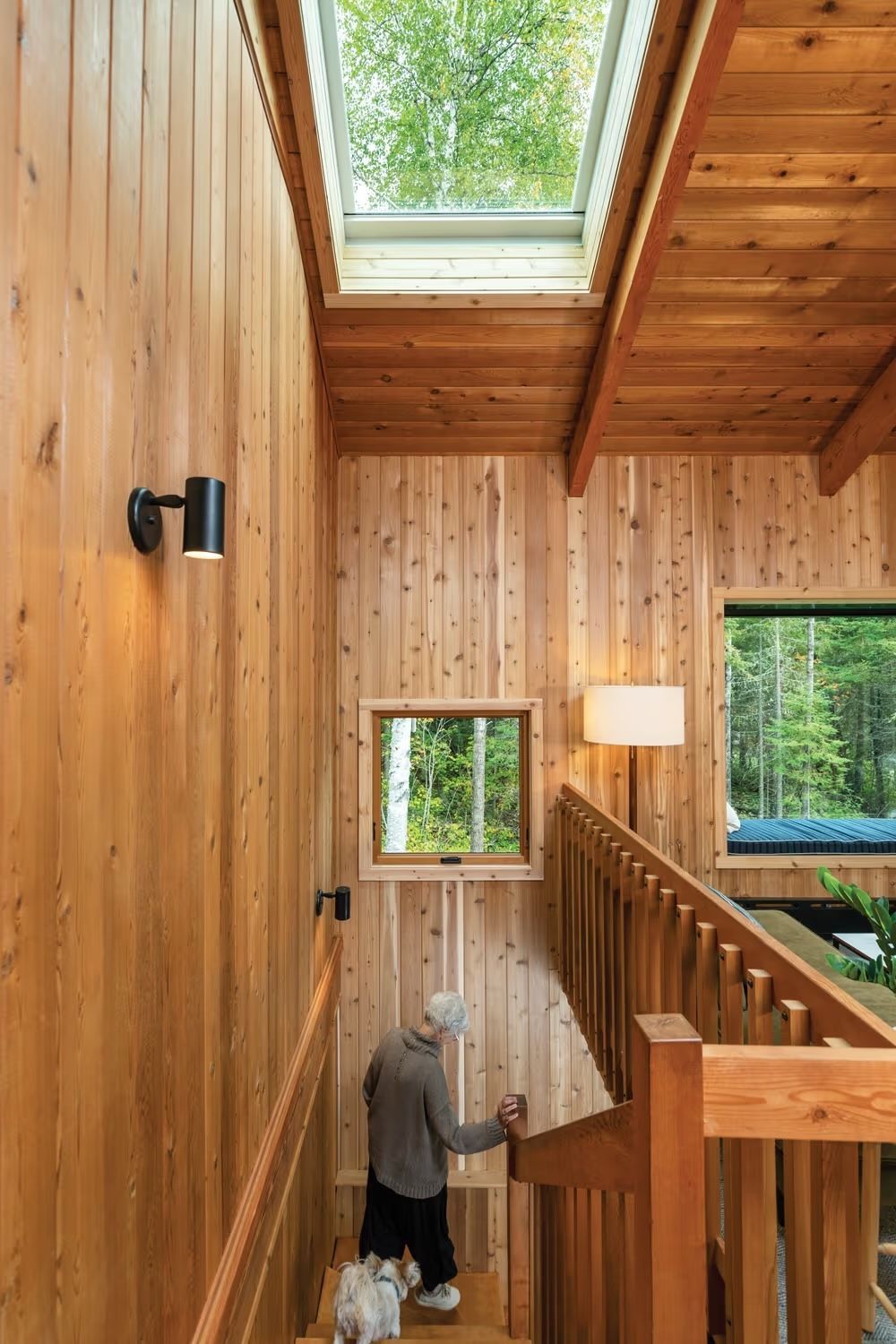 A man is walking down a set of stairs in a wooden house.