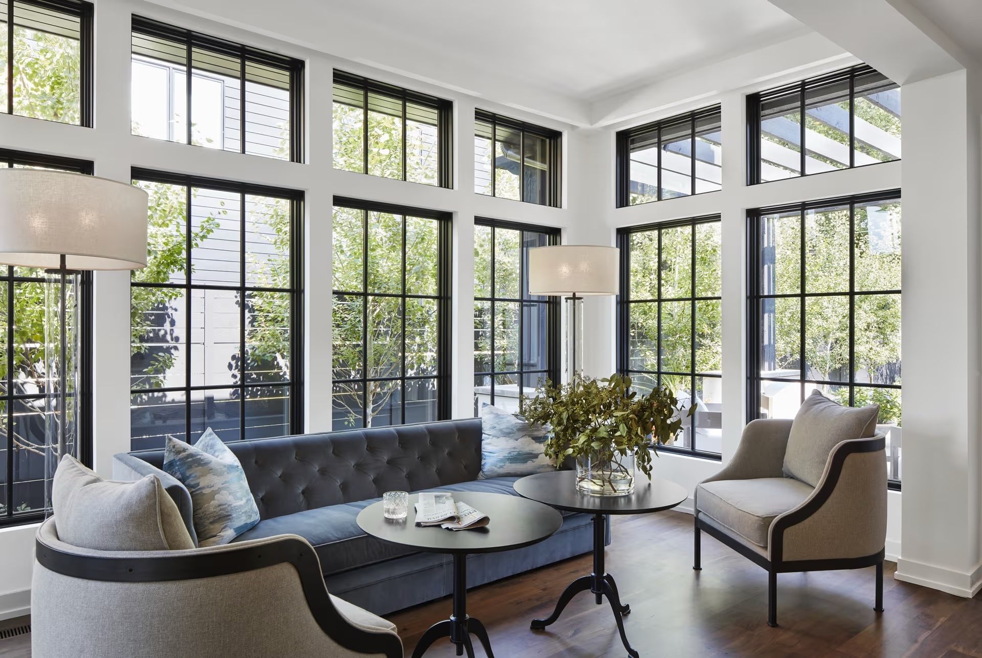 A living room with a couch and chairs and lots of windows