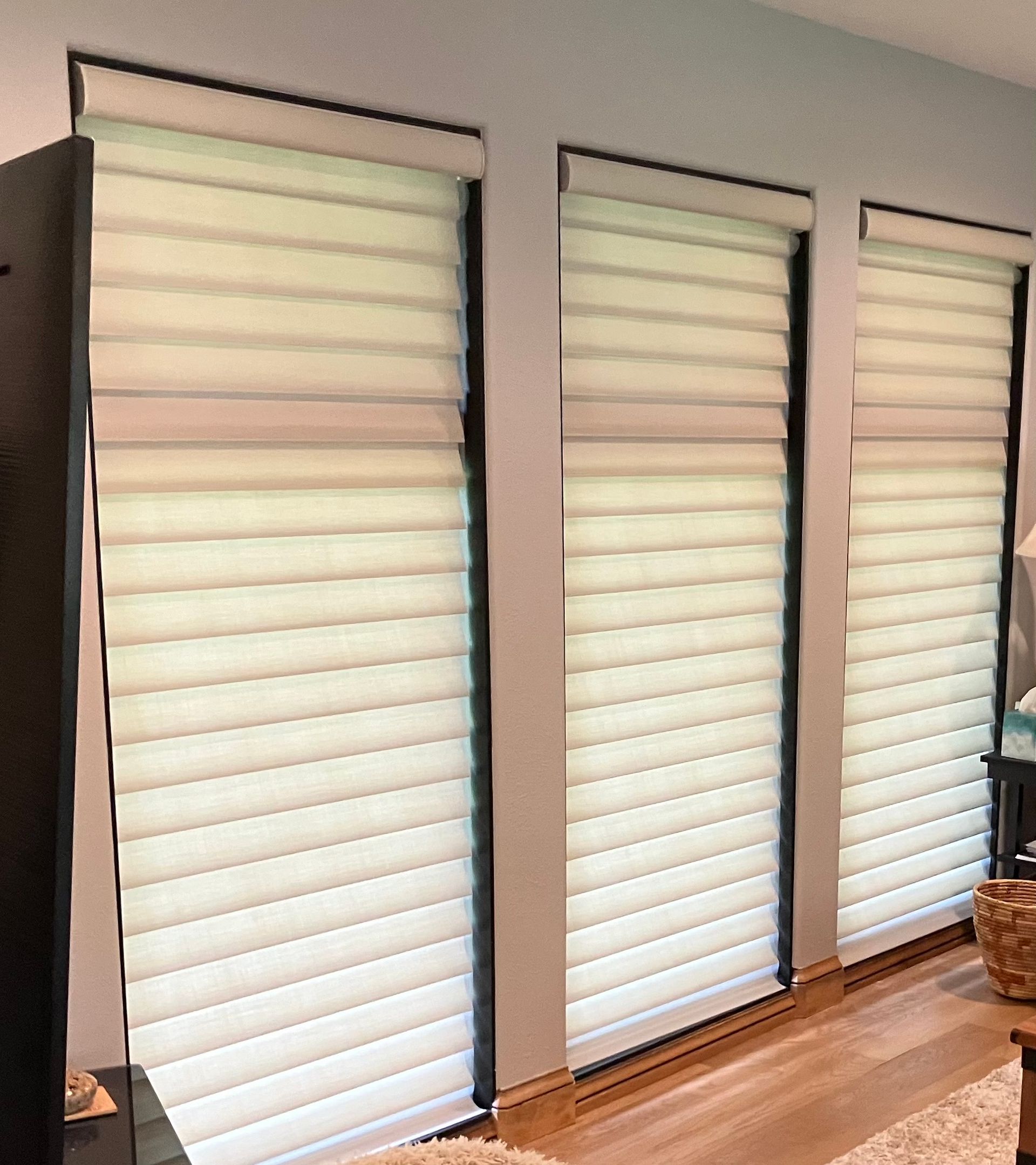A living room with three white blinds on the windows.