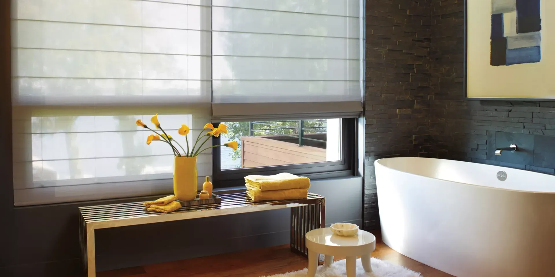 A bathroom with a tub and a window with roman shades.