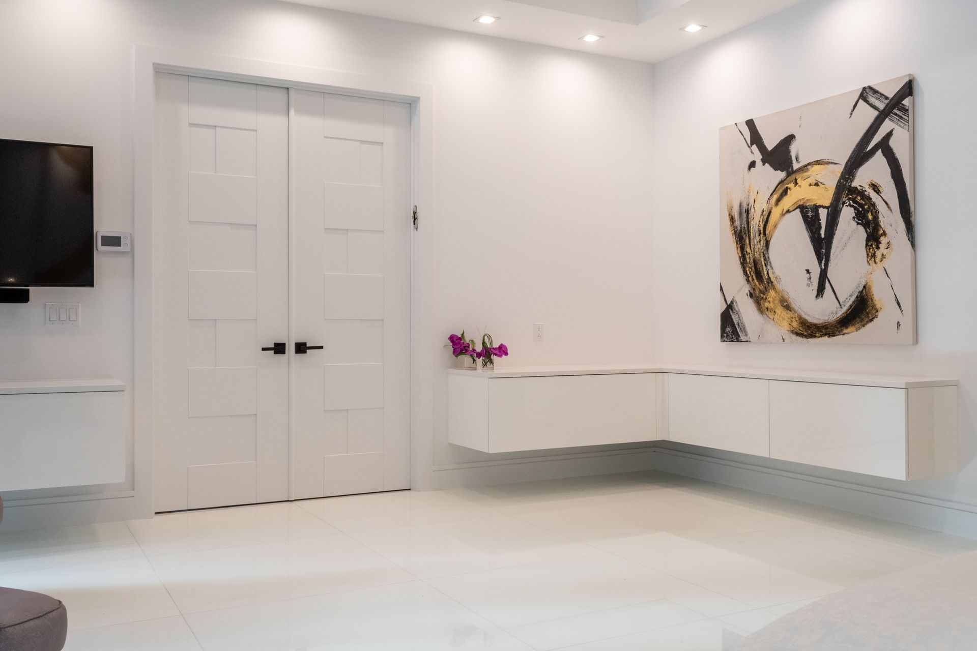 A living room with a painting on the wall and a television on the wall.