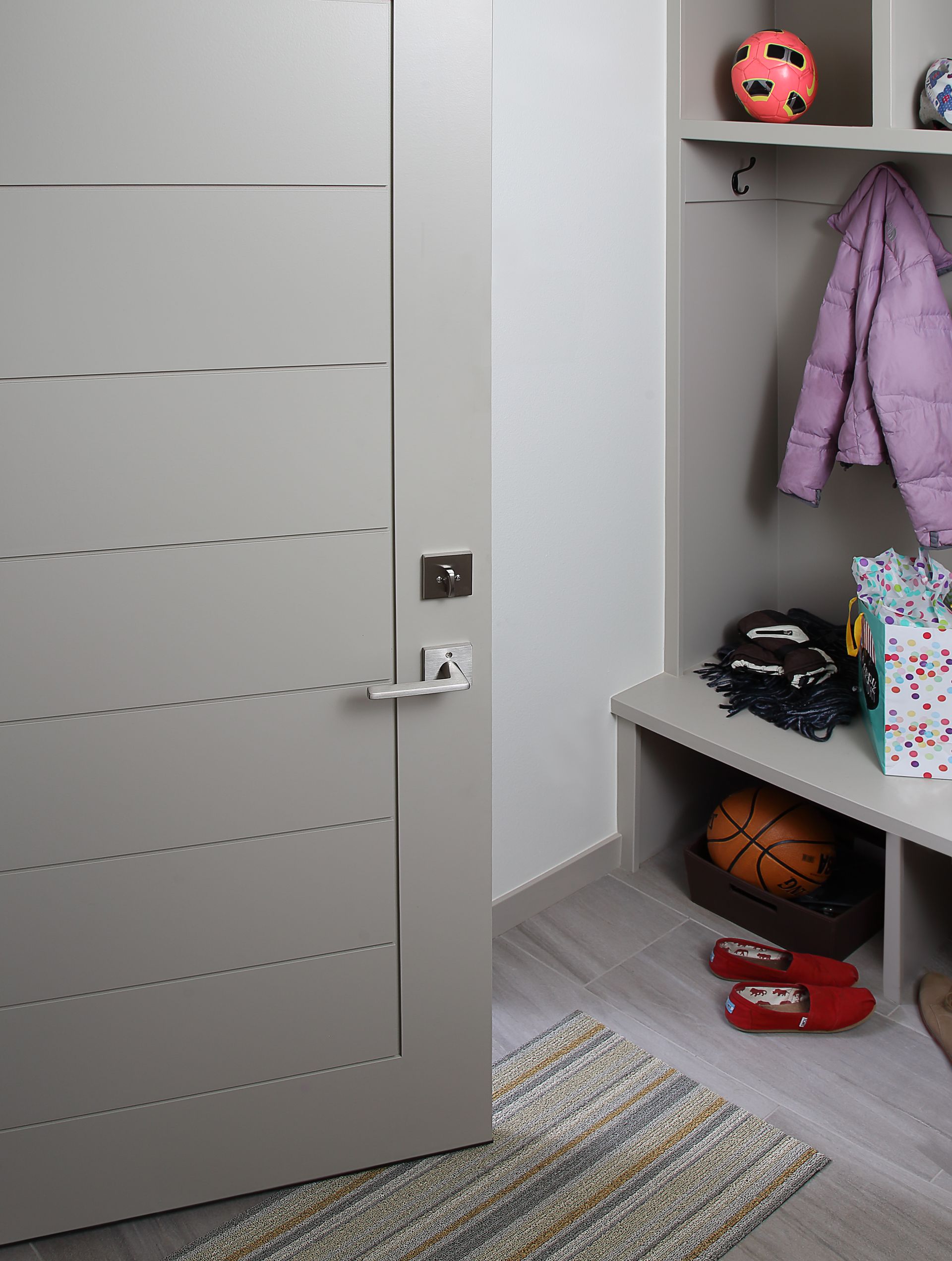 A door is open to a mud room with a bench and a shelf.
