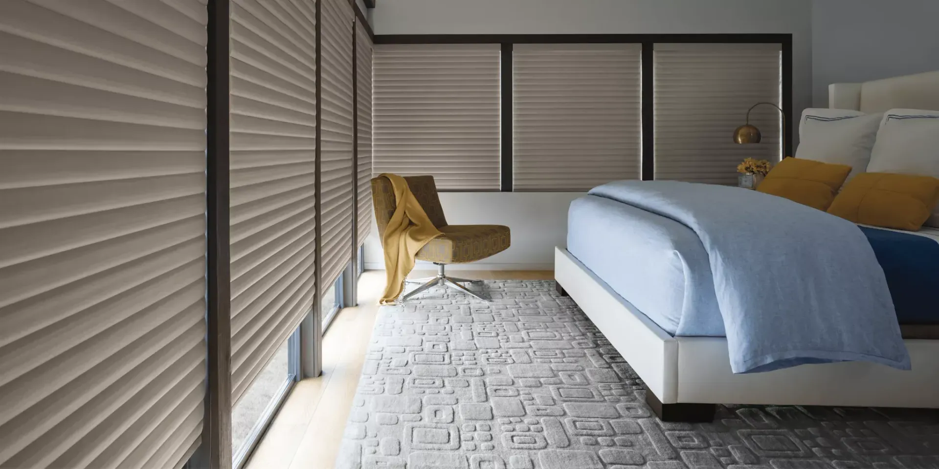 A bedroom with a bed , chair , rug and blinds.