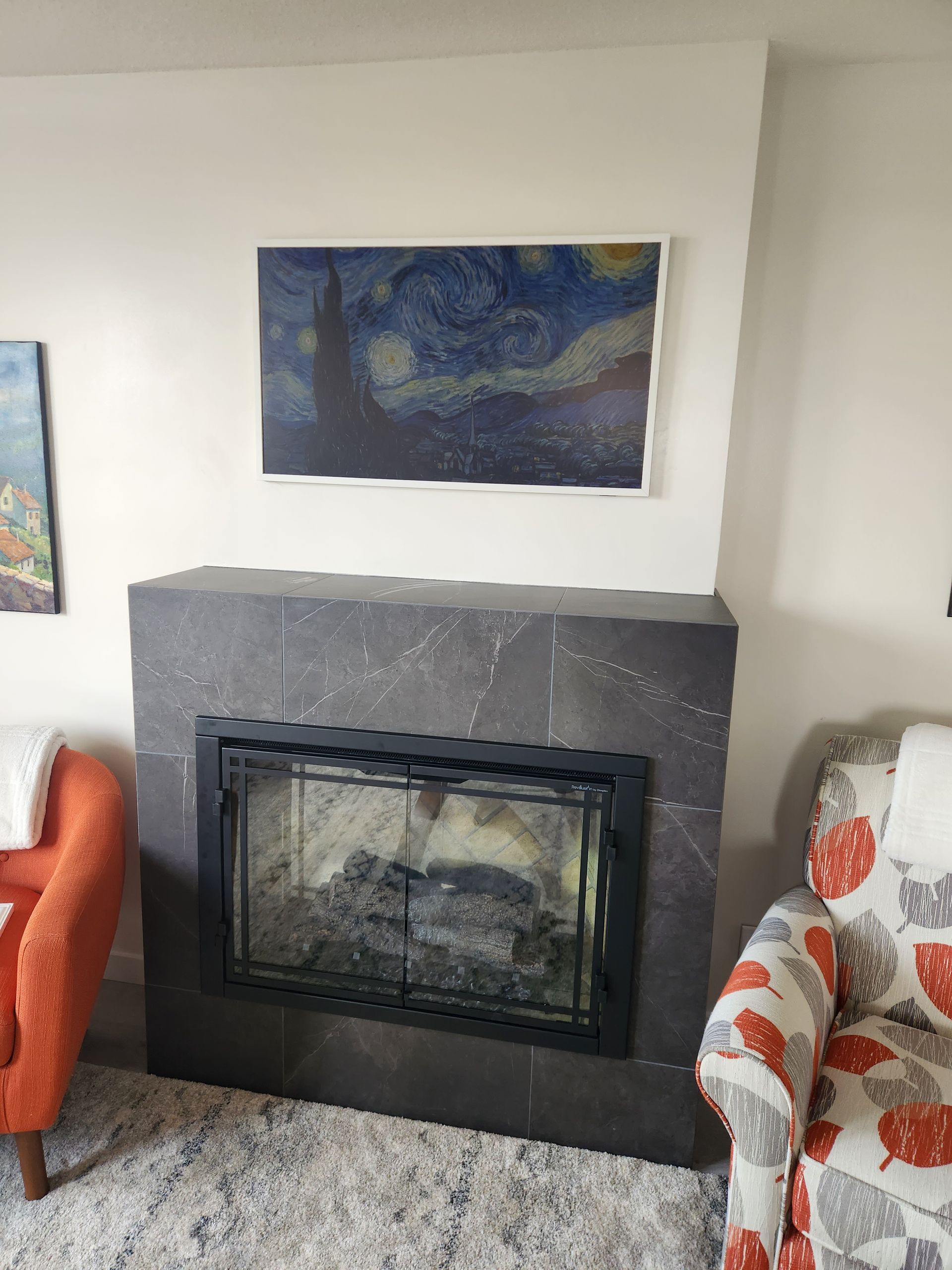 A living room with a fireplace and a painting on the wall above it.