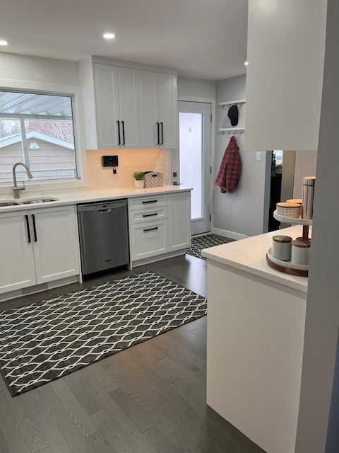 A kitchen with white cabinets and a rug on the floor