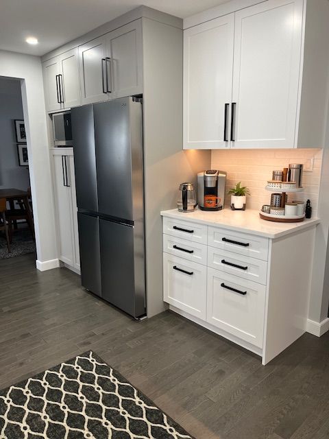 A kitchen with white cabinets and a stainless steel refrigerator.
