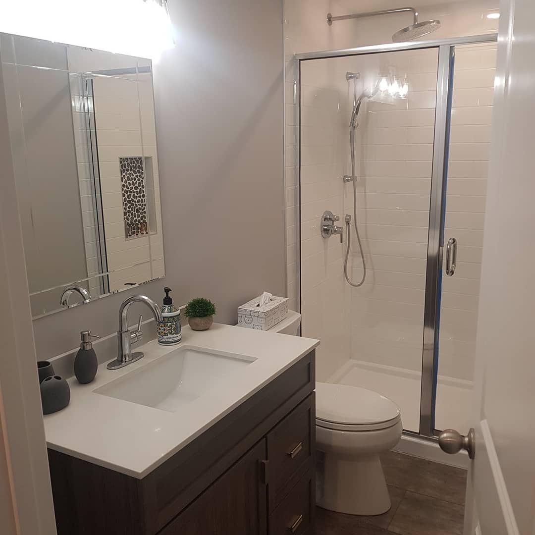 A bathroom with a sink , toilet , shower and mirror.