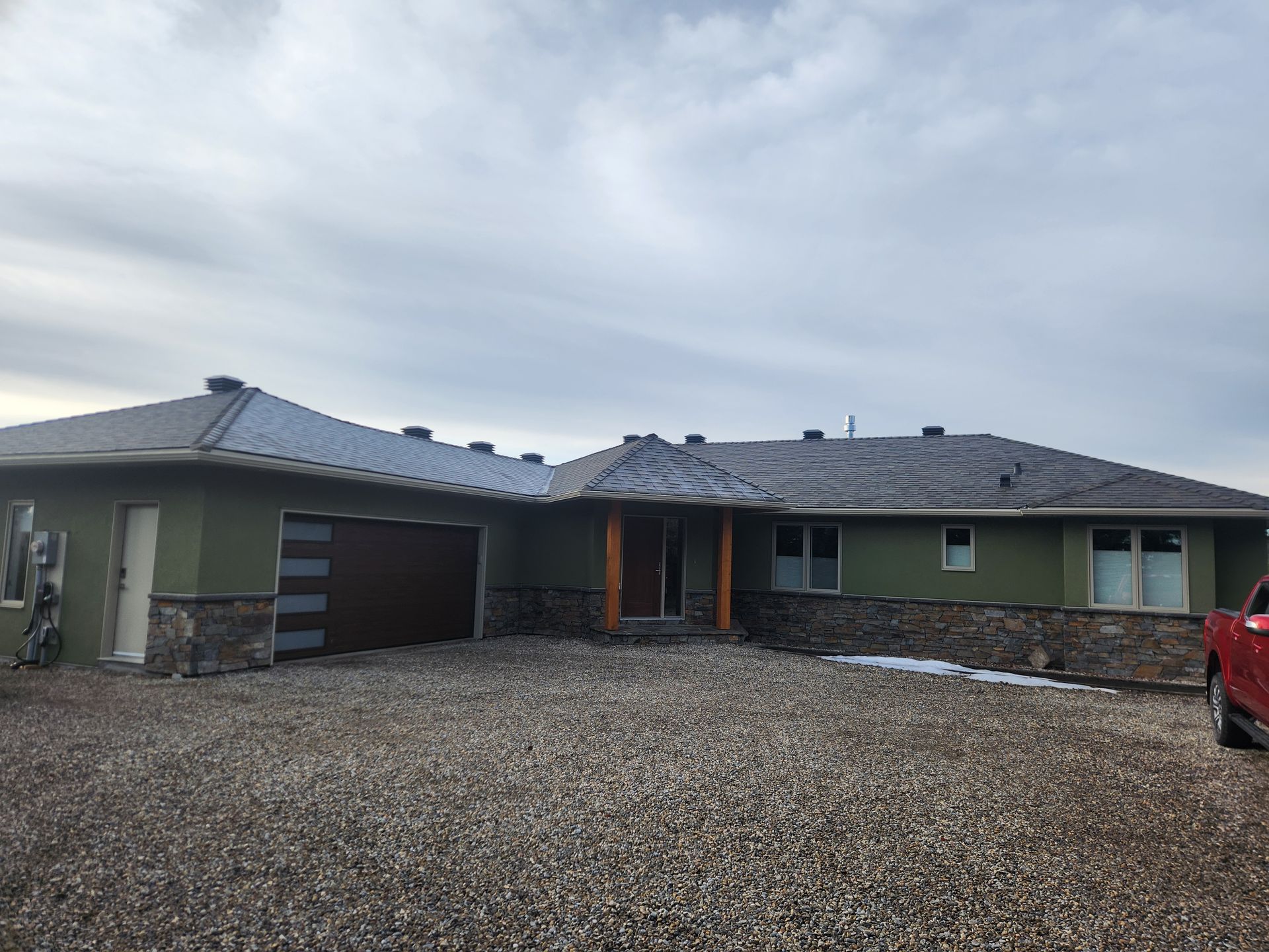 A green house with a red truck parked in front of it.