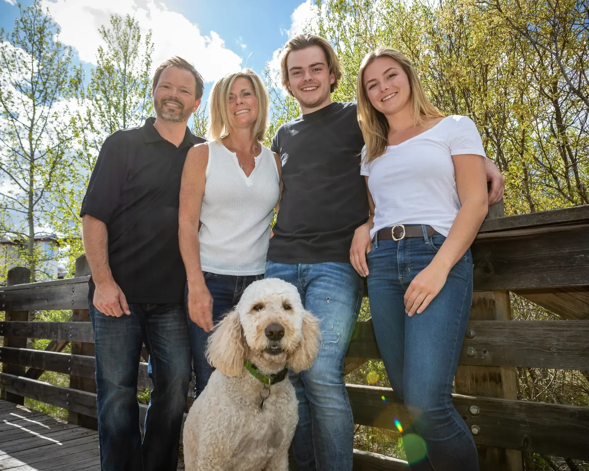A family posing for a picture with a dog on a bridge.
