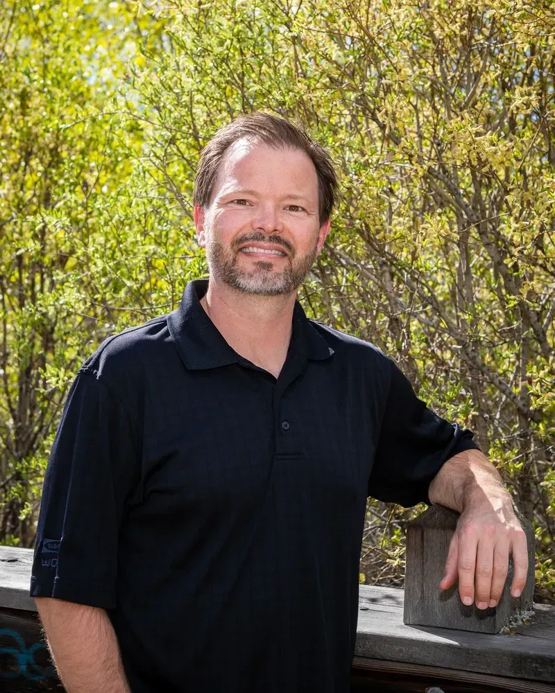 A man in a black shirt is leaning against a railing.