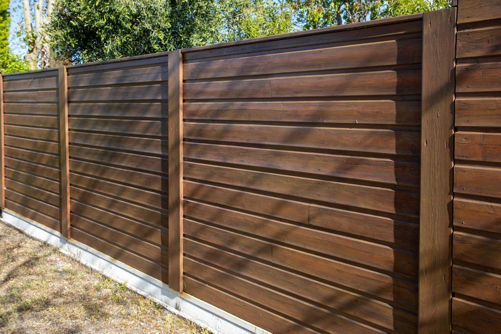 Wooden privacy fence with horizontal planks, dark brown color, outdoors.