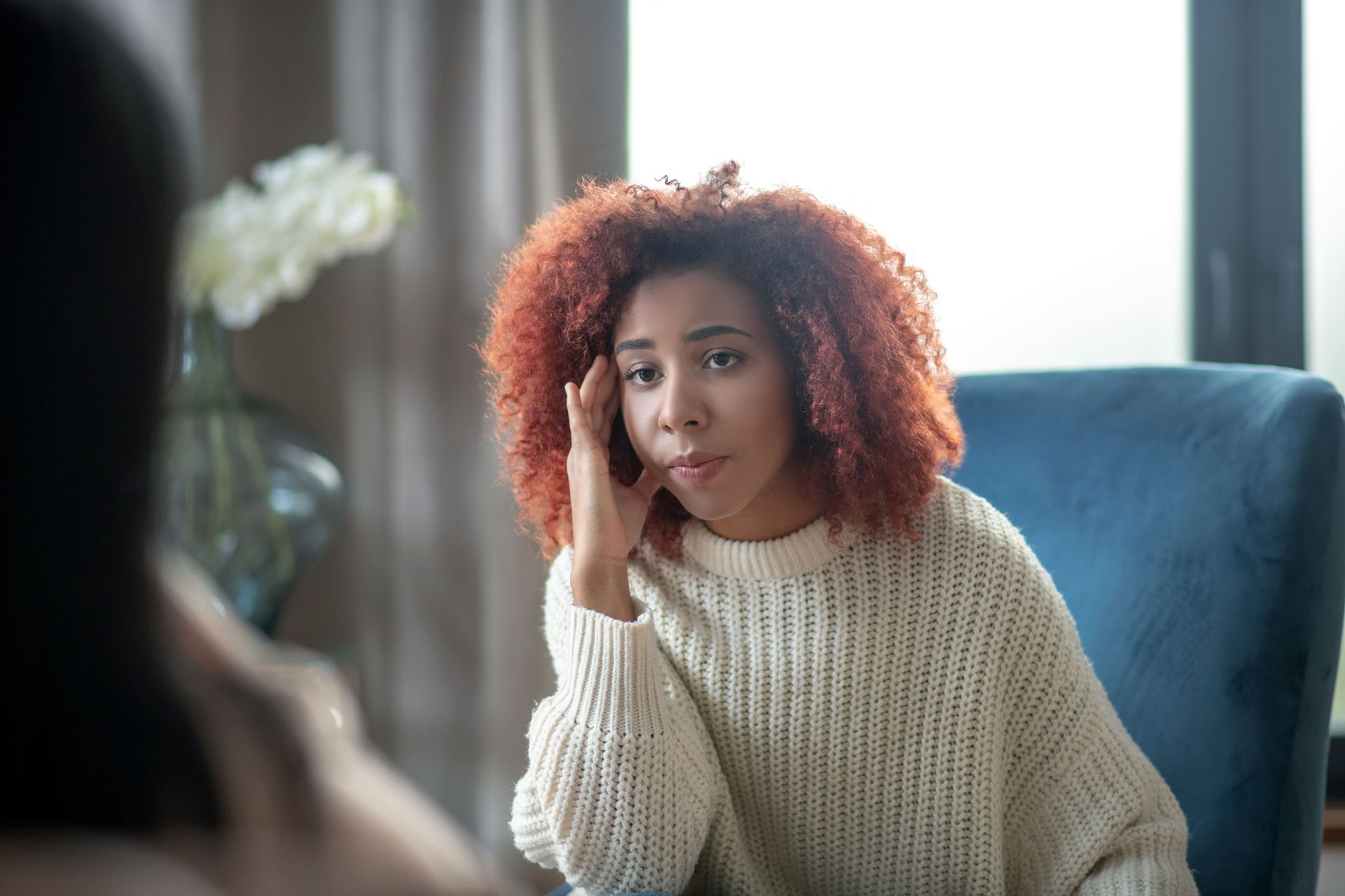 A man is sitting on a couch talking to a woman.