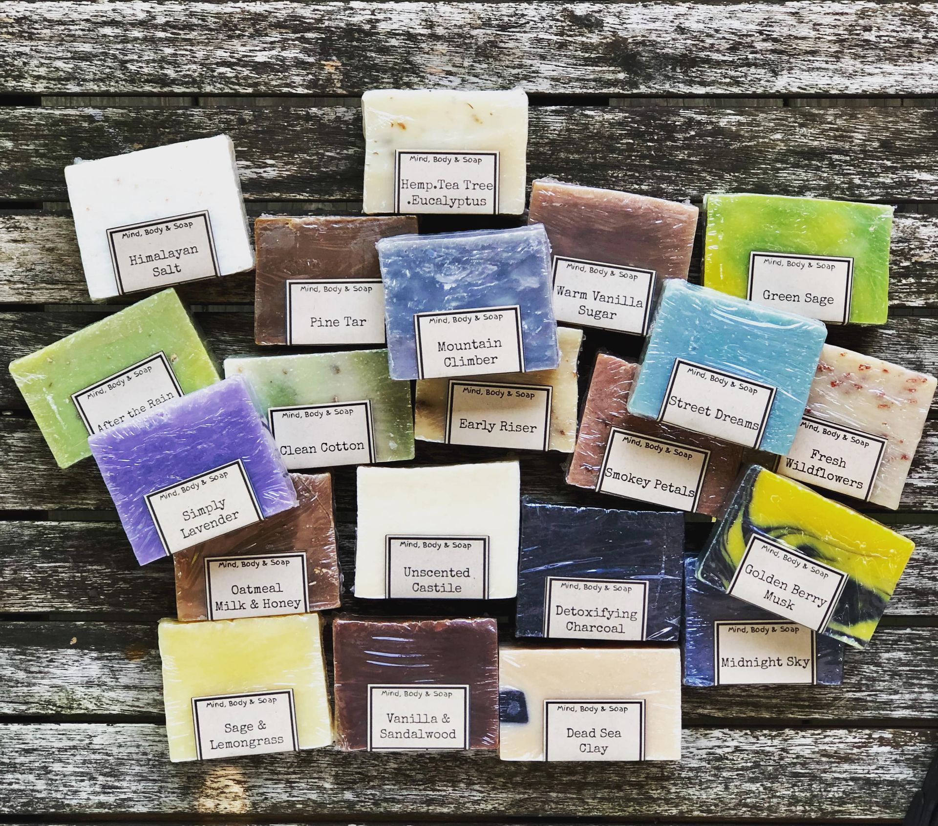 Assortment of colorful soap bars on a rustic wooden surface, each with a label.