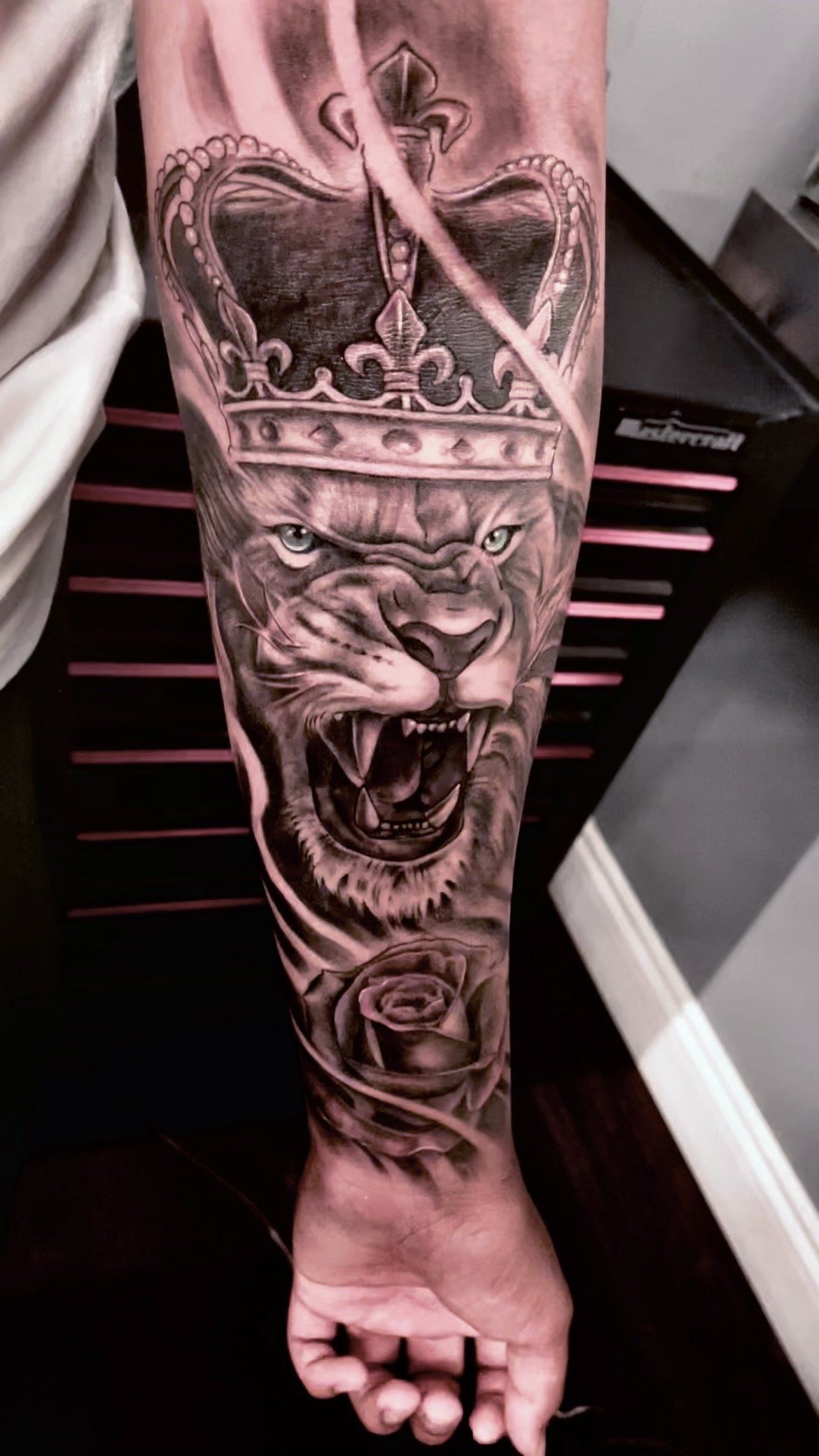 A man has a tattoo of a lion with a crown on his forearm