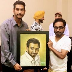 Two men are holding a framed portrait of a man.