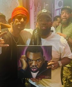 Two men are standing next to each other holding a painting of ice cube.
