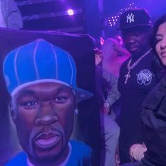 A man and a woman are standing next to a painting of a man in a blue hat.