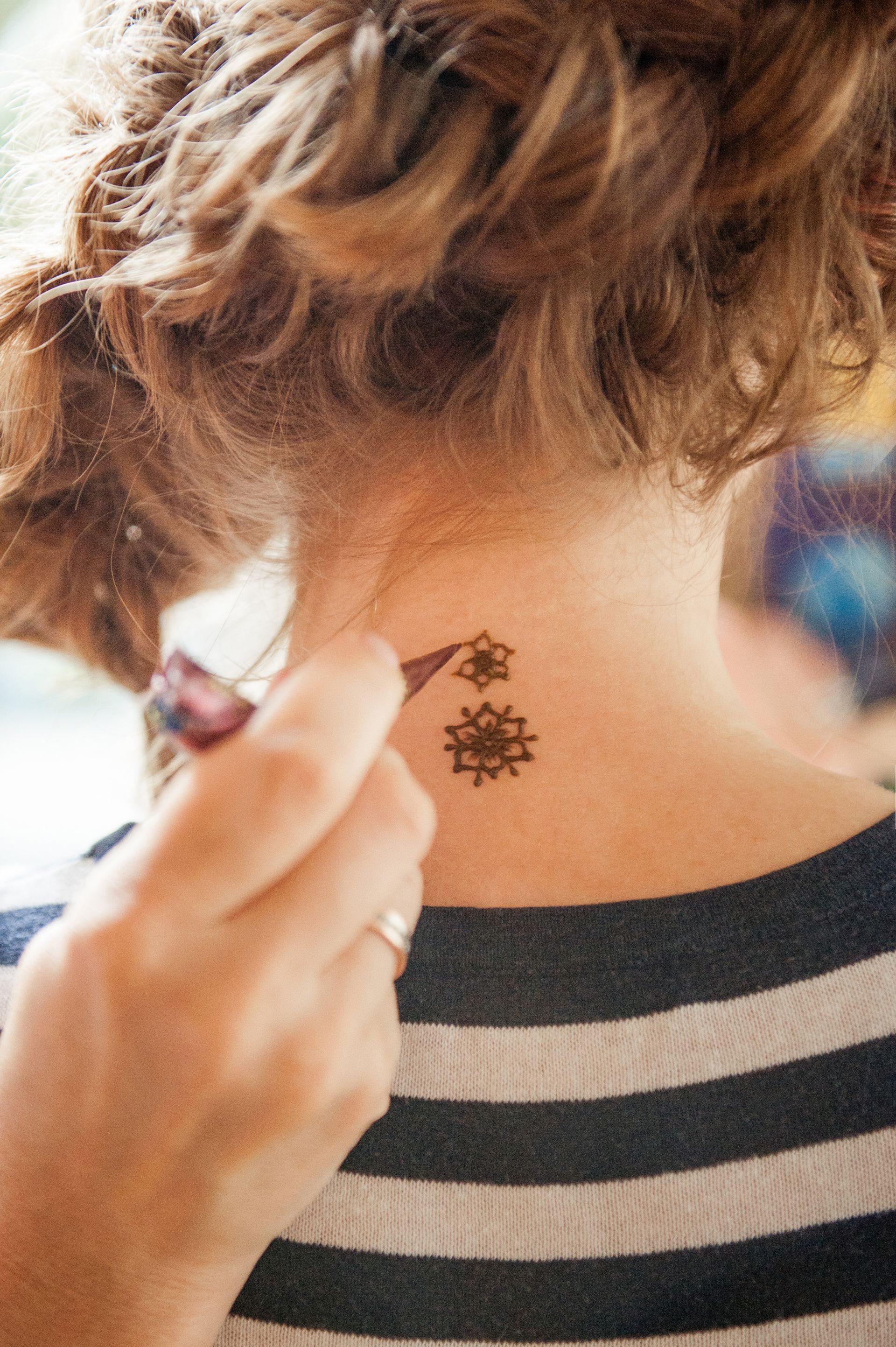 A woman is getting a tattoo on the back of her neck.