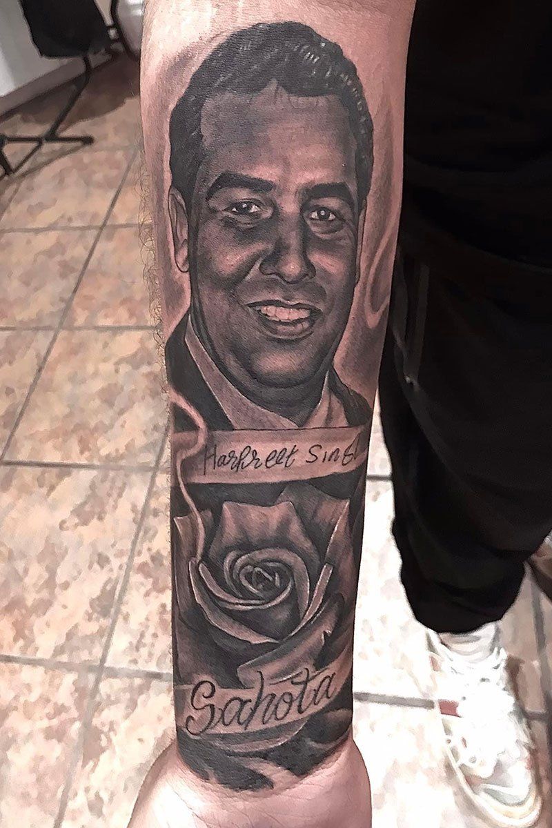 A man has a tattoo of a man and a rose on his arm.