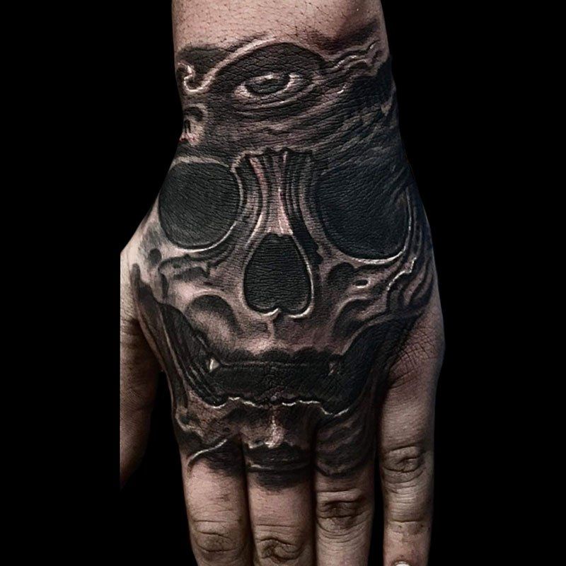 A close up of a person 's hand with a skull tattoo on it.