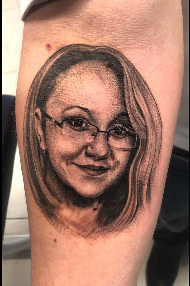 A black and white tattoo of a woman 's face with glasses