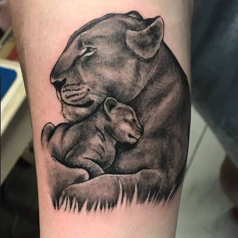 A tattoo of a lioness holding her cub on a person 's arm.