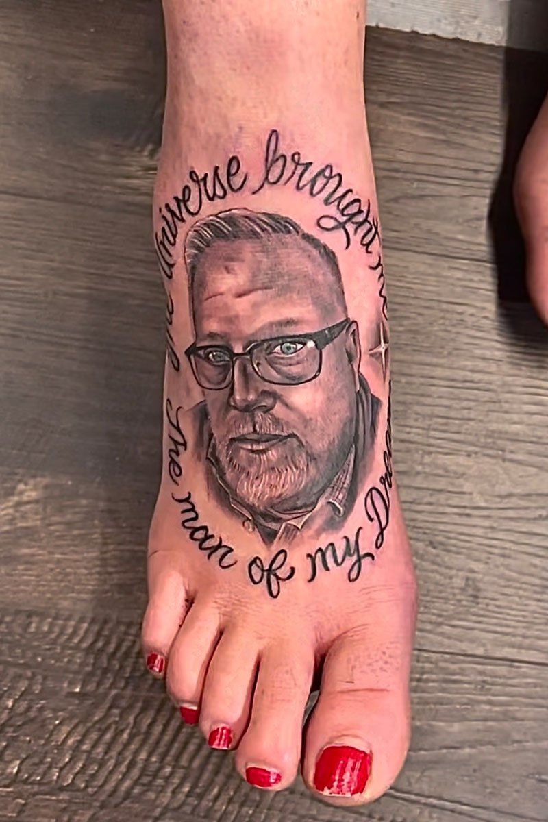A woman has a tattoo of a man 's face on her foot.