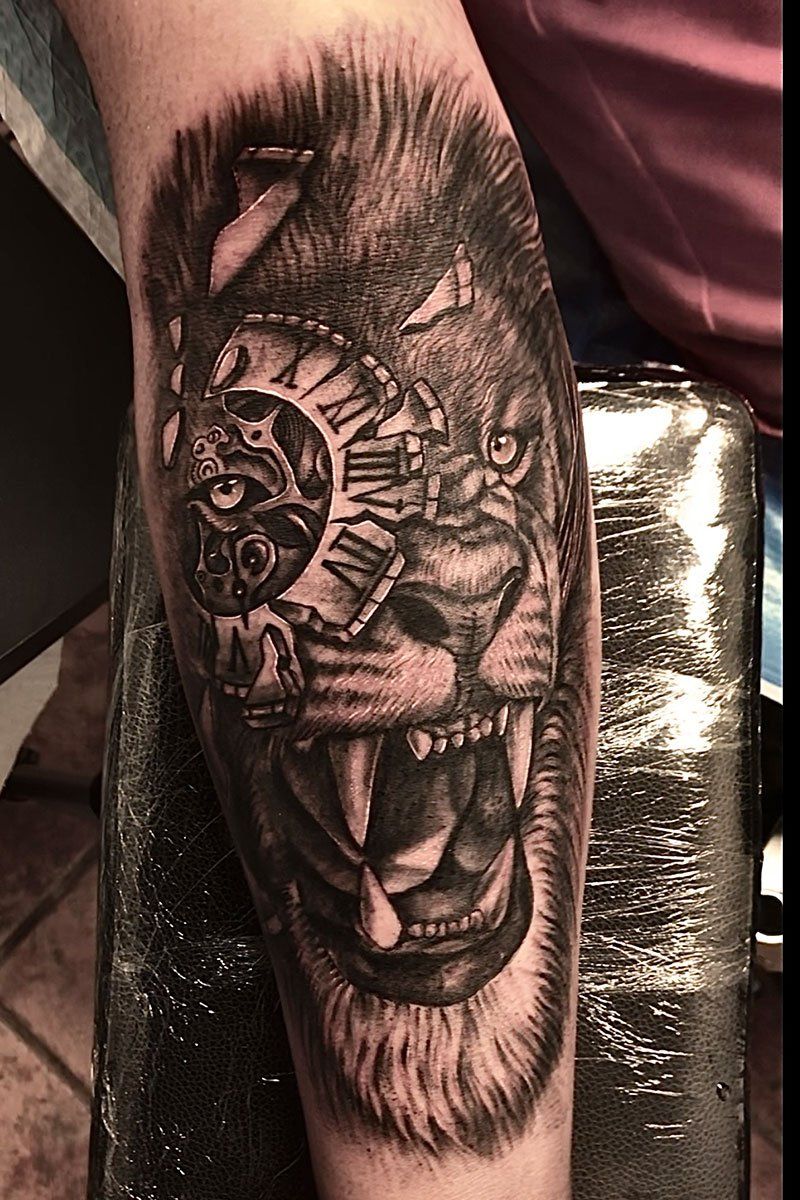A tattoo of a lion with a clock in its eye