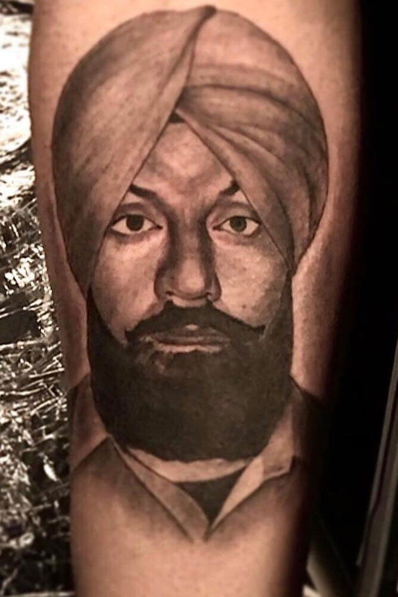 A black and white tattoo of a man with a beard wearing a turban.