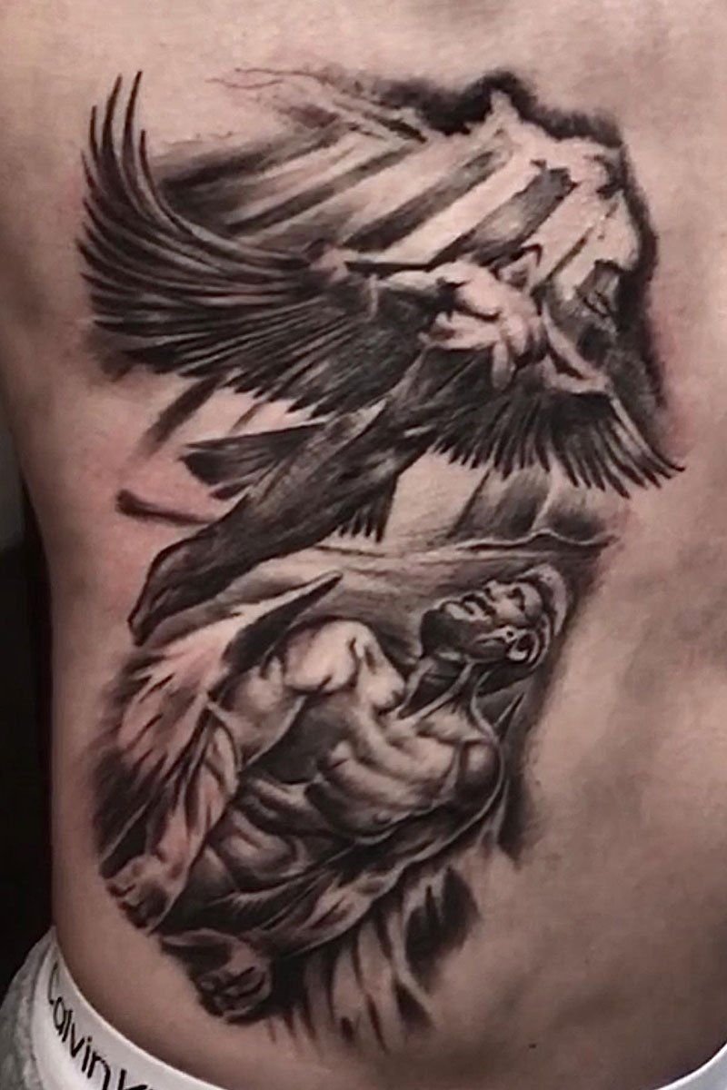 A black and white tattoo of two angels flying over a man.