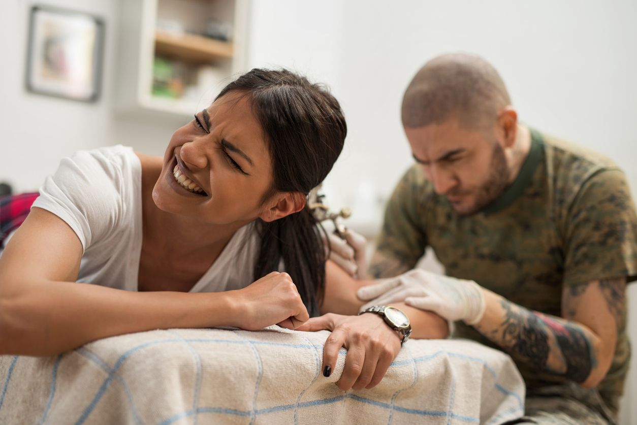 A woman is getting a tattoo on her arm.