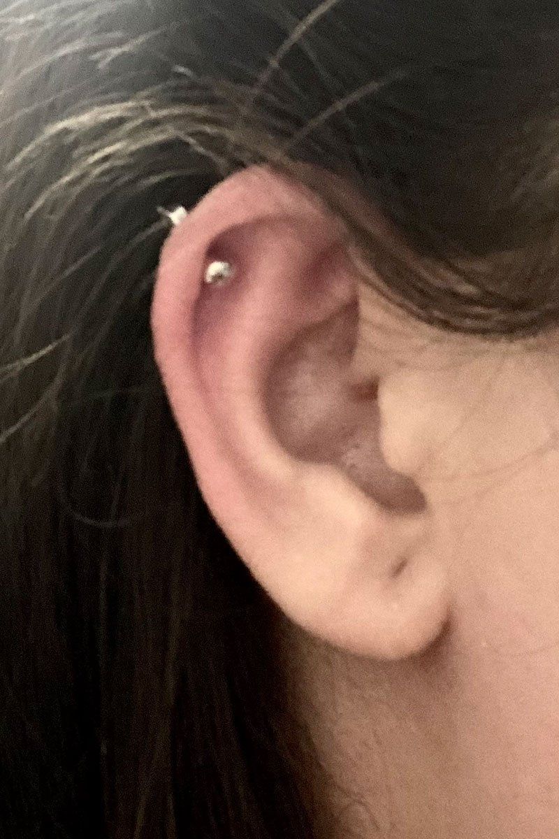 A close up of a person 's ear with a piercing