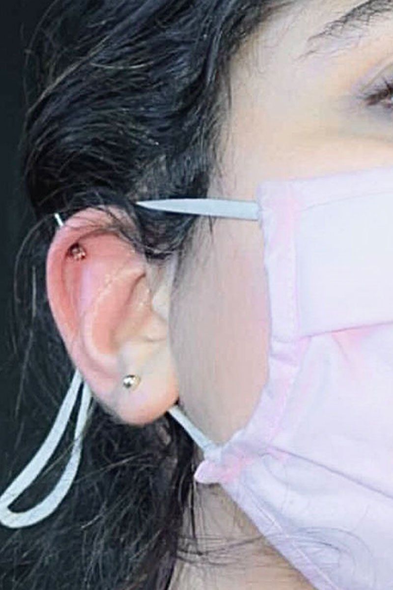 A close up of a woman wearing a pink mask and earrings.