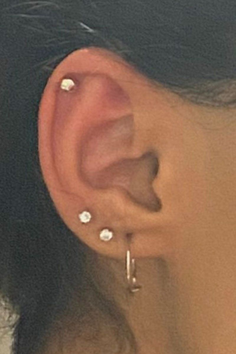 A close up of a woman 's ear with three piercings.