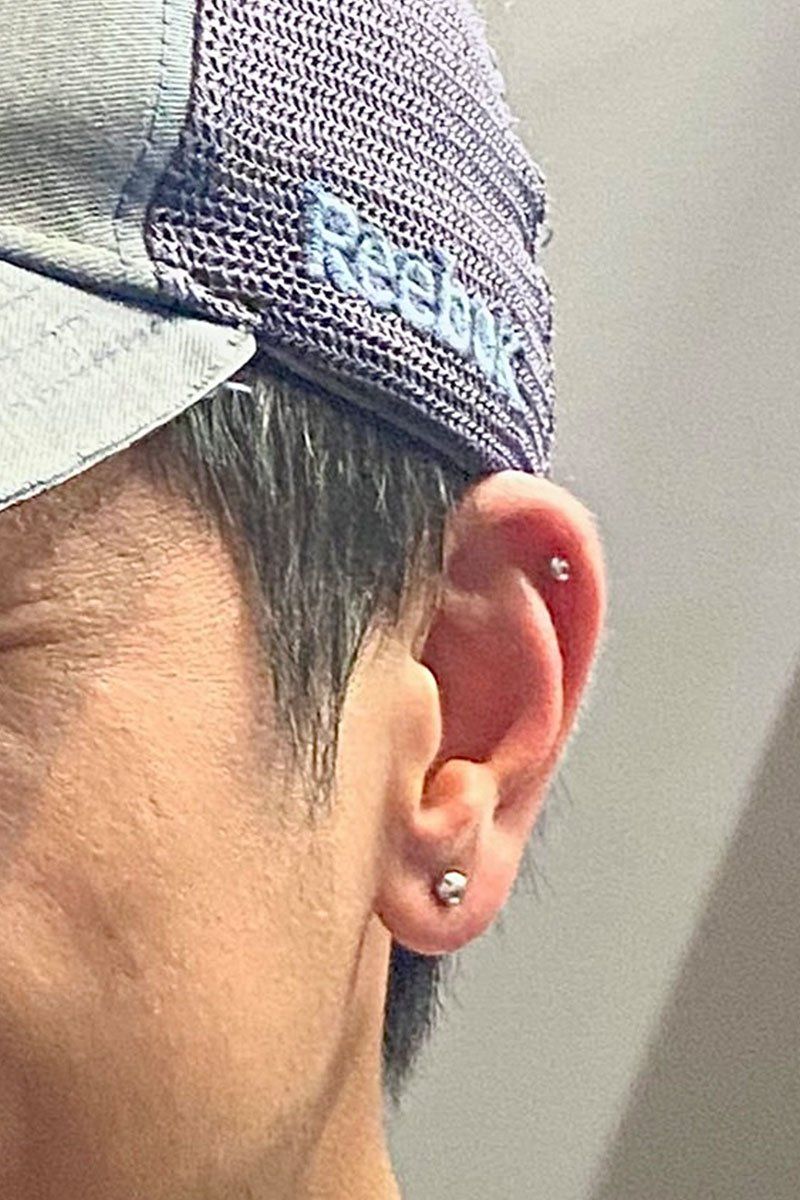 A close up of a man 's ear with a hat on.