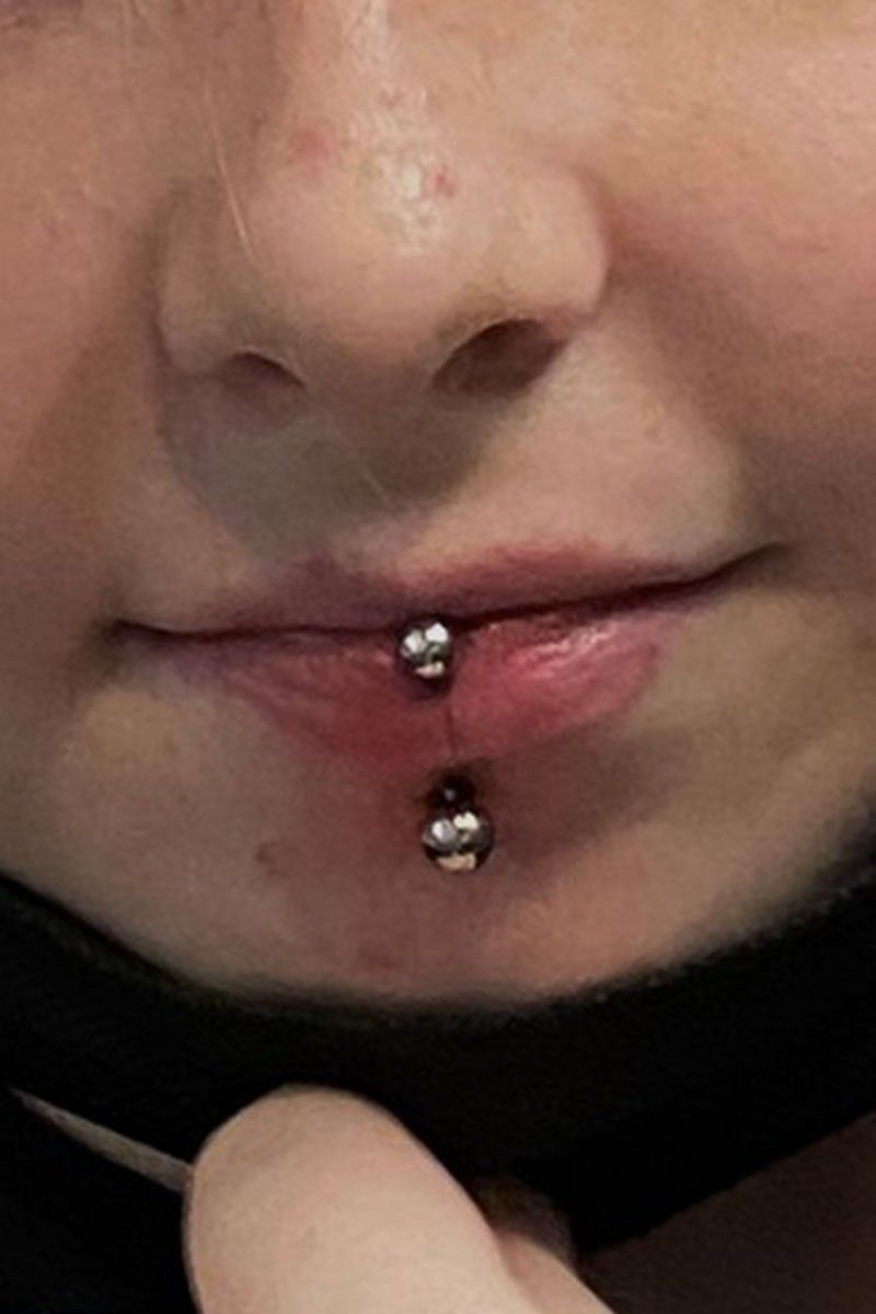 A close up of a person 's mouth with a lip piercing.