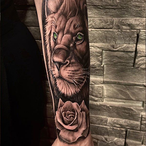 A man has a tattoo of a lion and a rose on his forearm.