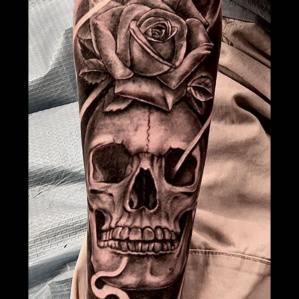 A tattoo of a skull with a rose and a snake