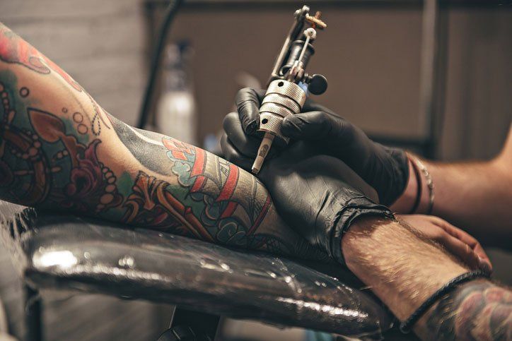 A man is getting a tattoo on his arm.