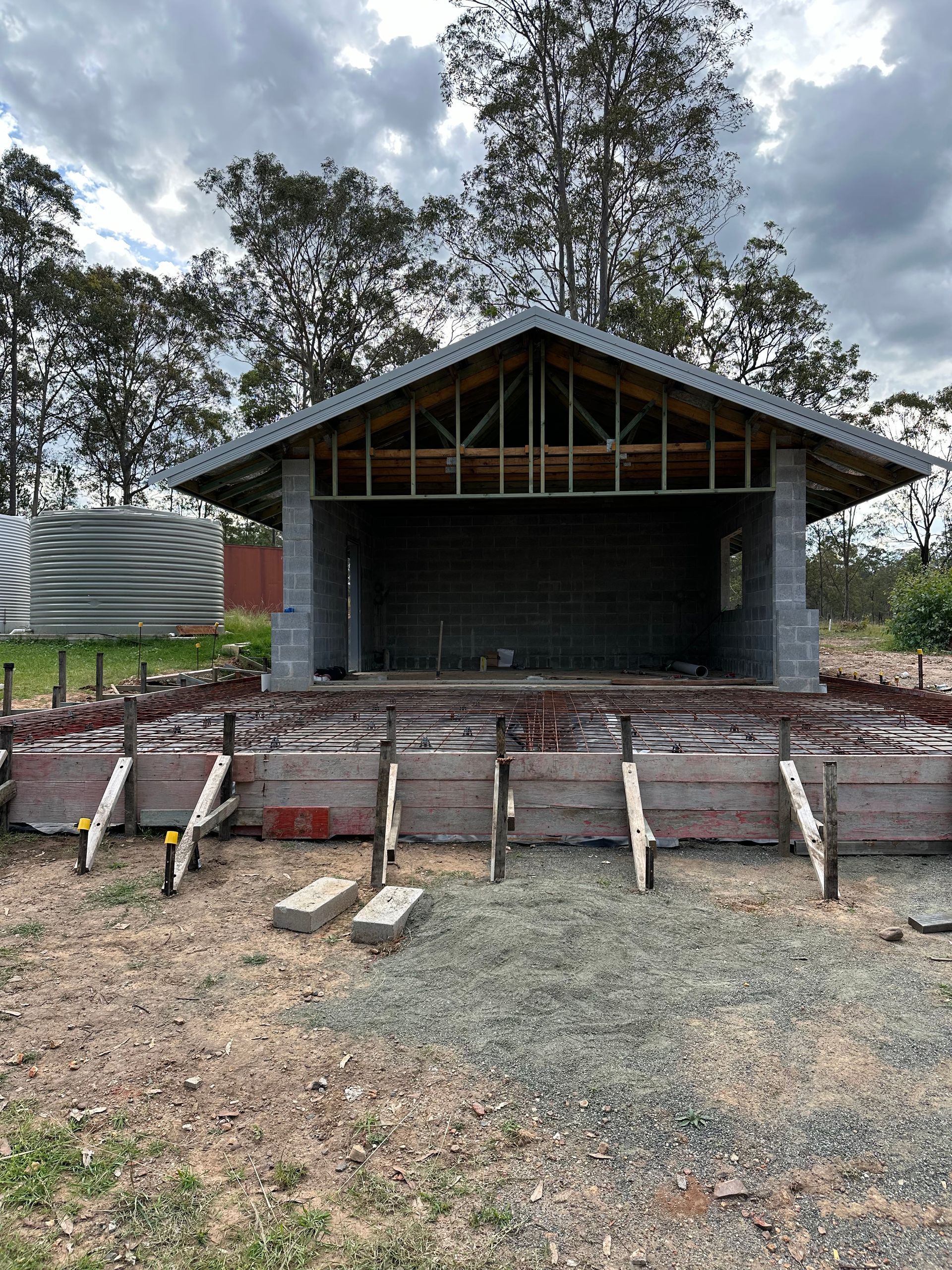A small building is being built in the middle of a dirt field.