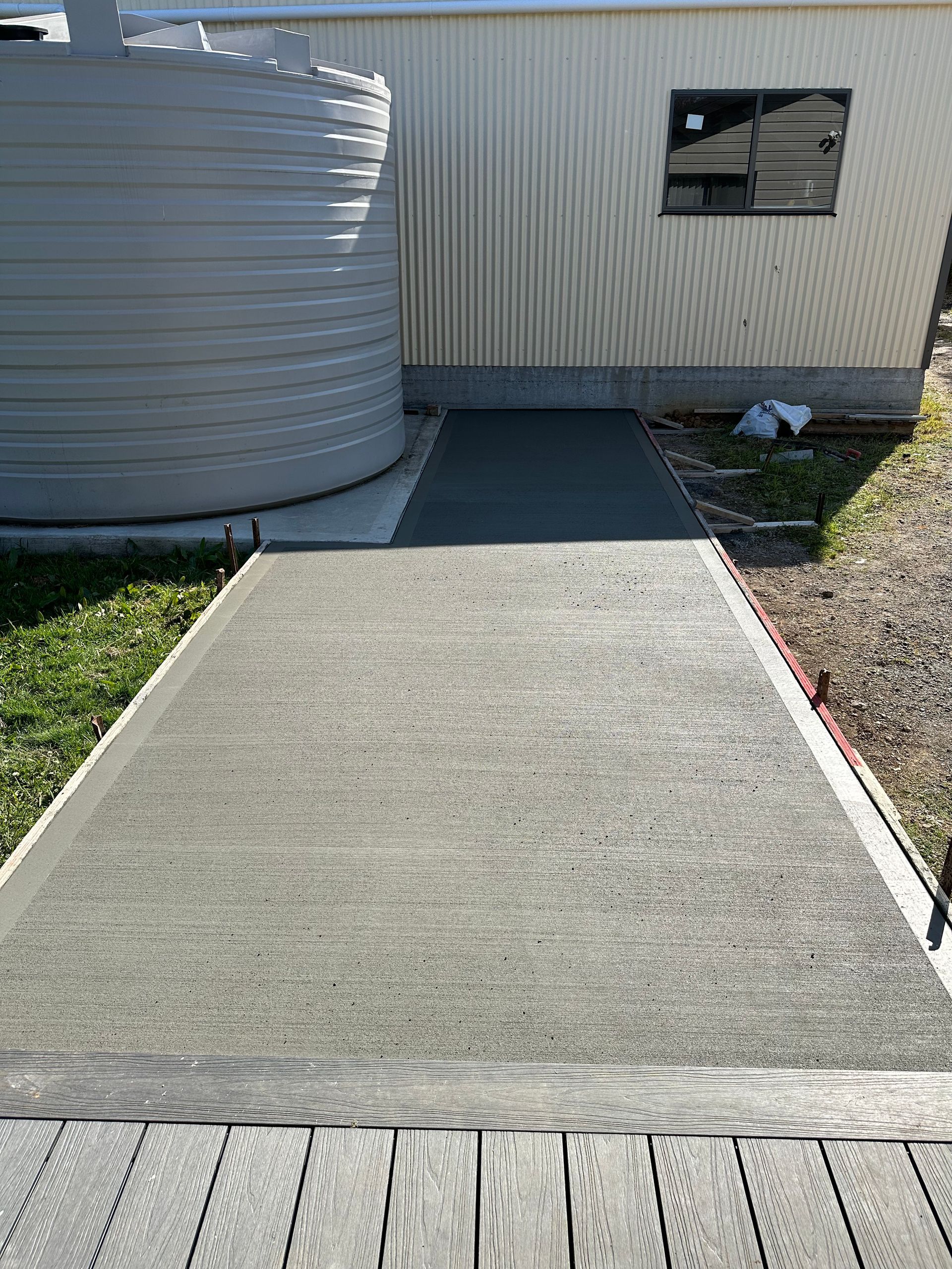 A concrete walkway leading to a building with a water tank in the background.
