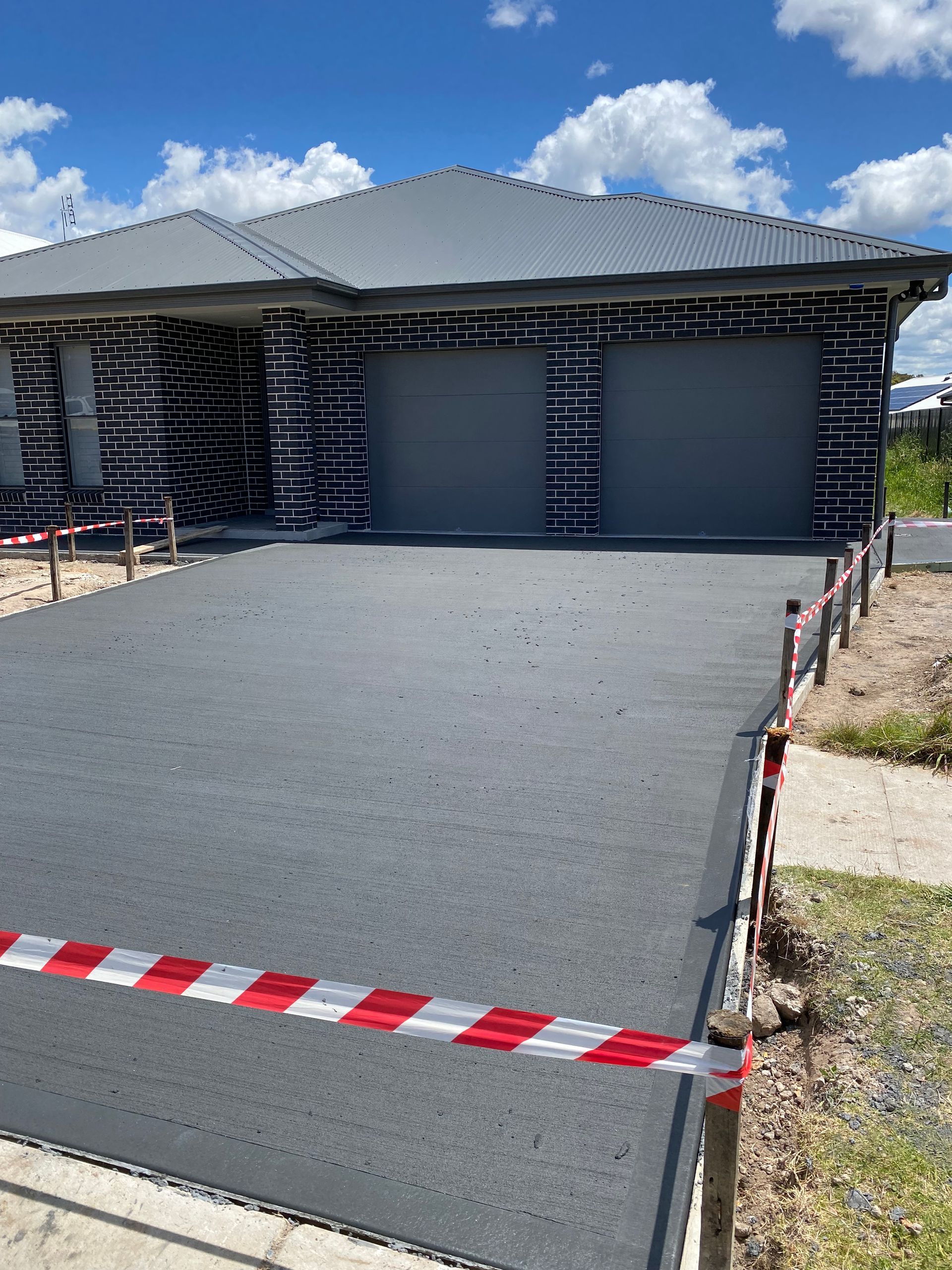 A house is being built with a concrete driveway in front of it.