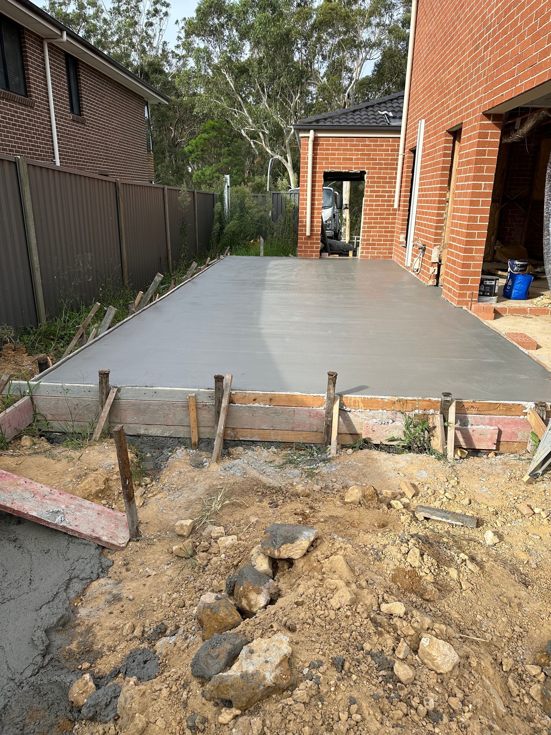 A concrete driveway is being built in front of a brick house.