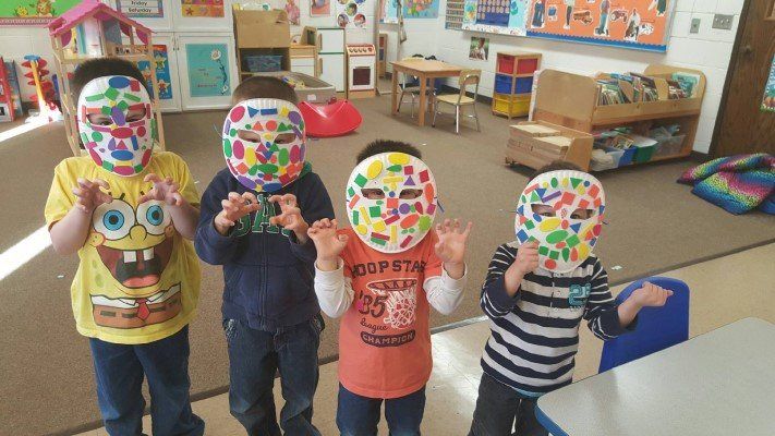 A group of children wearing colorful masks in a classroom