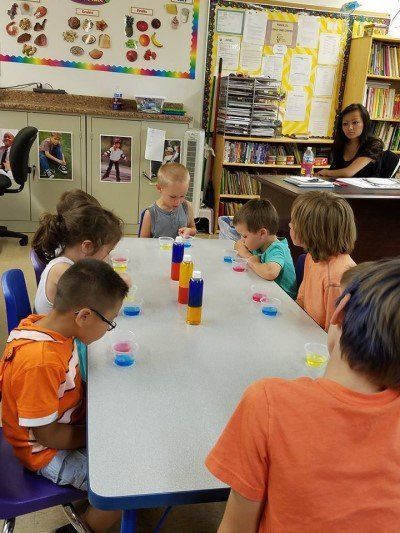 A group of children are sitting at a table in a classroom