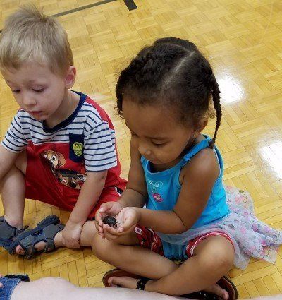 A boy and a girl are sitting on the floor playing with a toy.