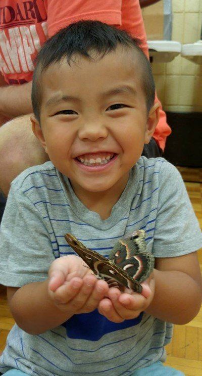 A young boy is holding a snake in his hands and smiling.
