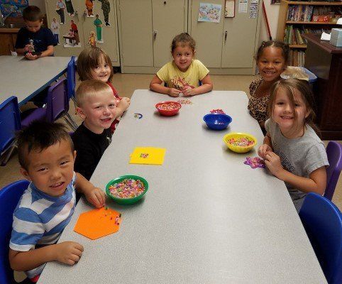 A group of children are sitting at a table with bowls of candy.