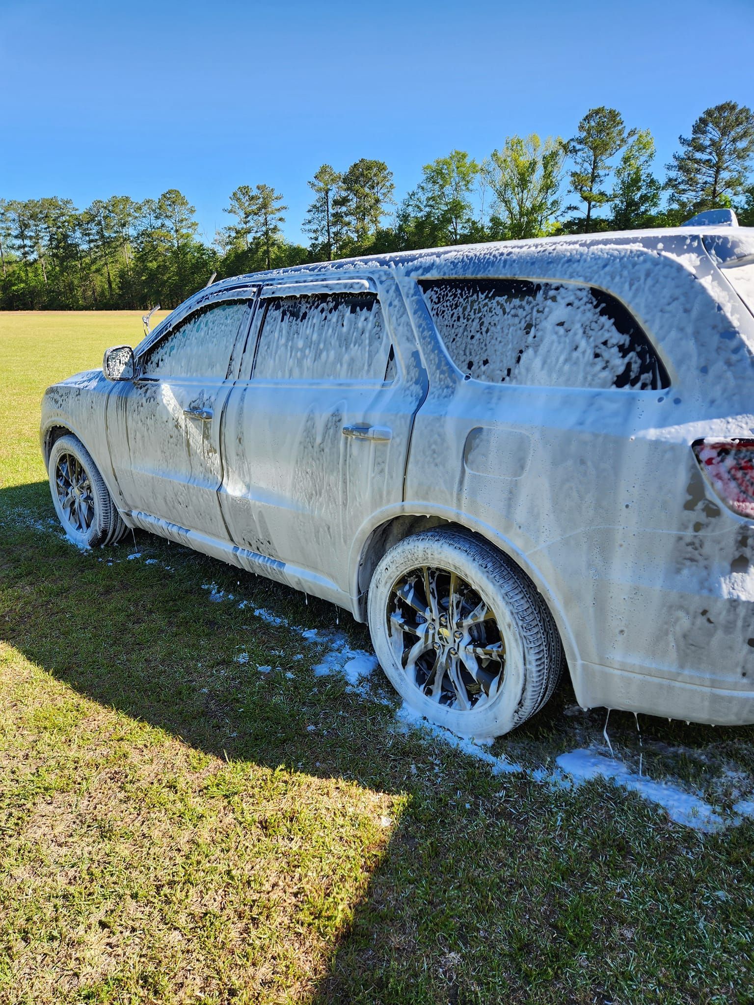 A White Suv Covered in Thick Soap Suds Parked on a Grassy Field — Valentine Detailing LLC in Walterboro, SC