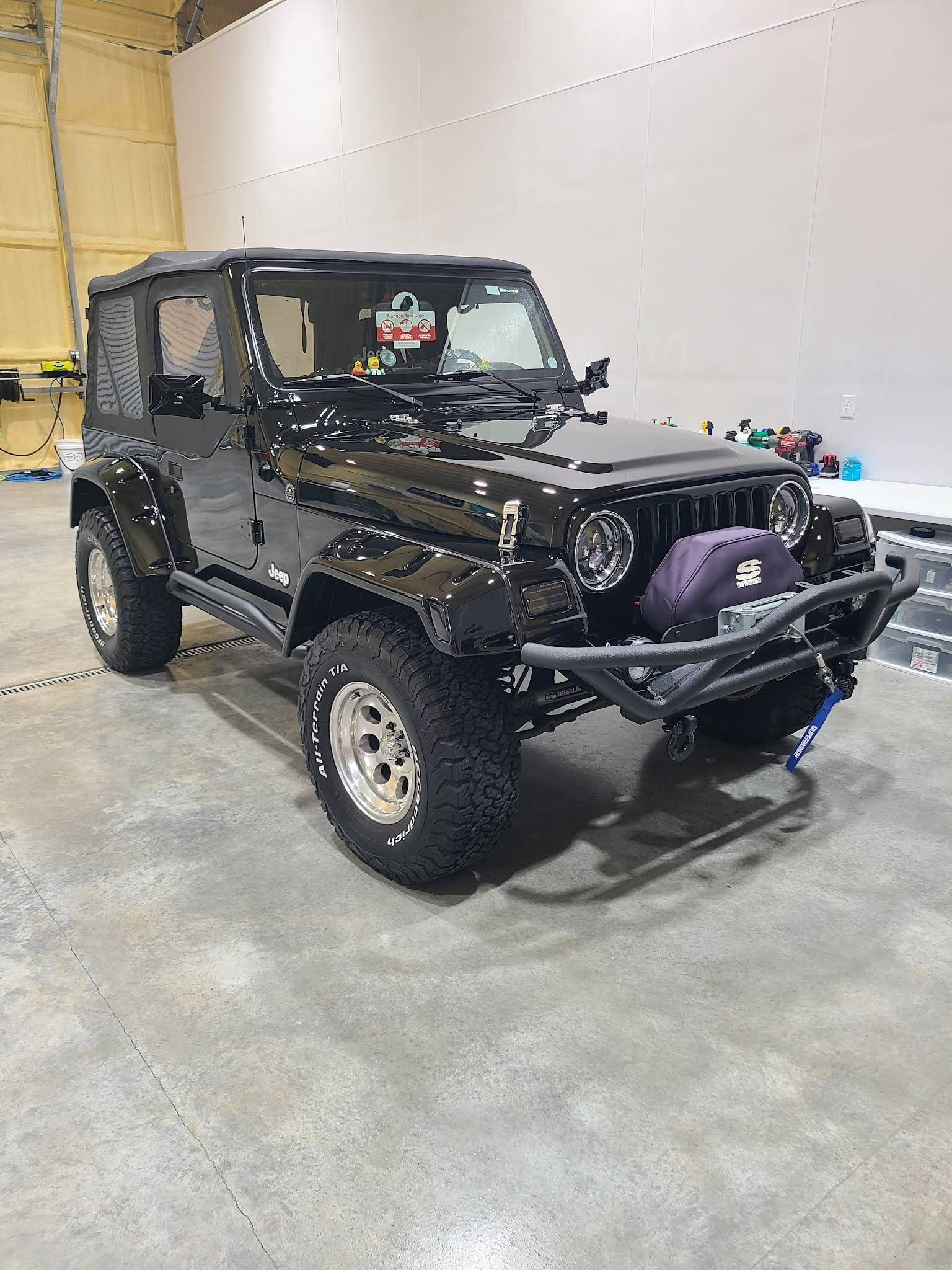 A Black Jeep Wrangler With Oversized Tires and a Front Bumper Winch — Valentine Detailing LLC in Walterboro, SC